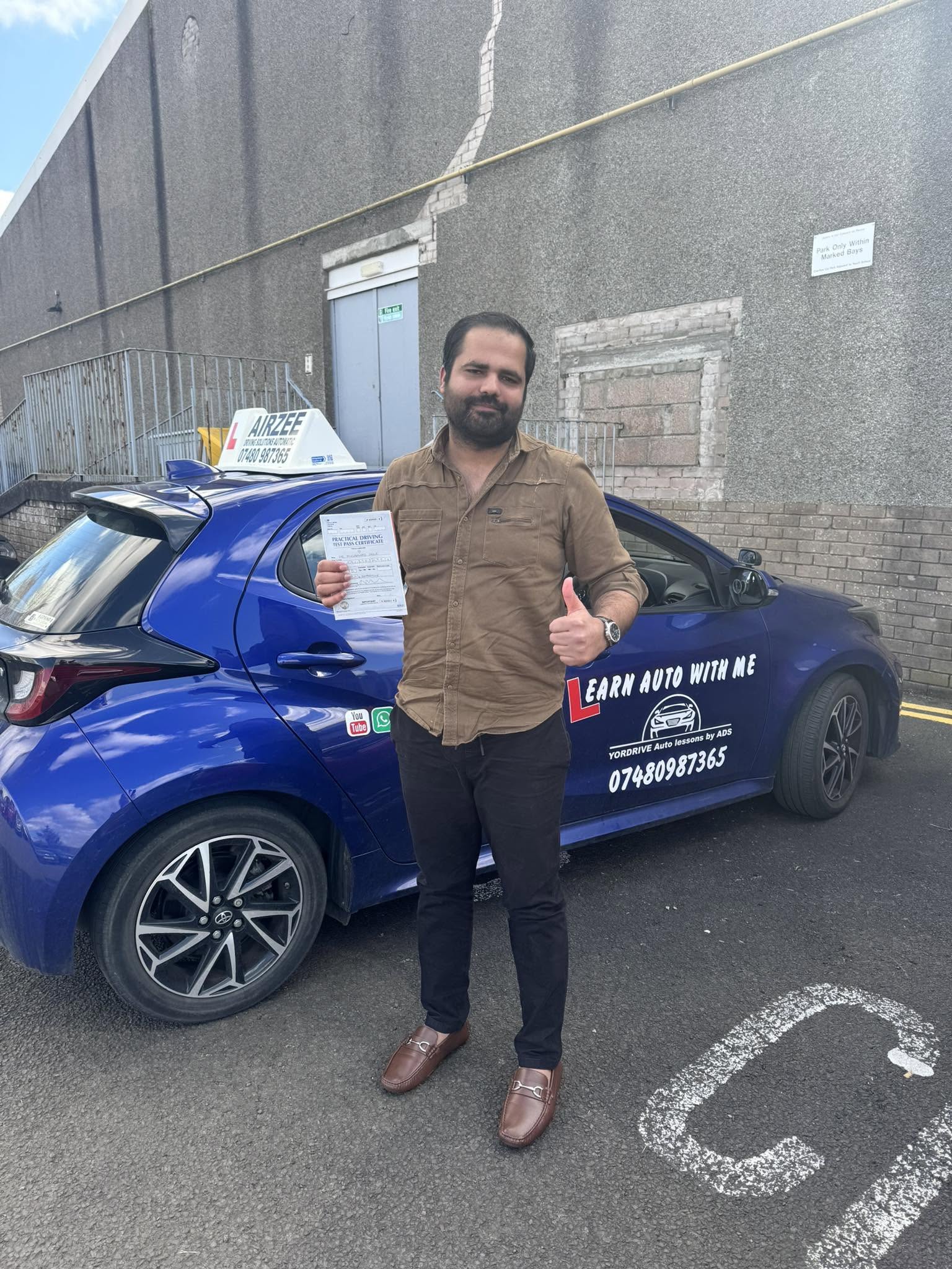 YorDrive learner celebrating with practical driving test pass certificate, blue training car