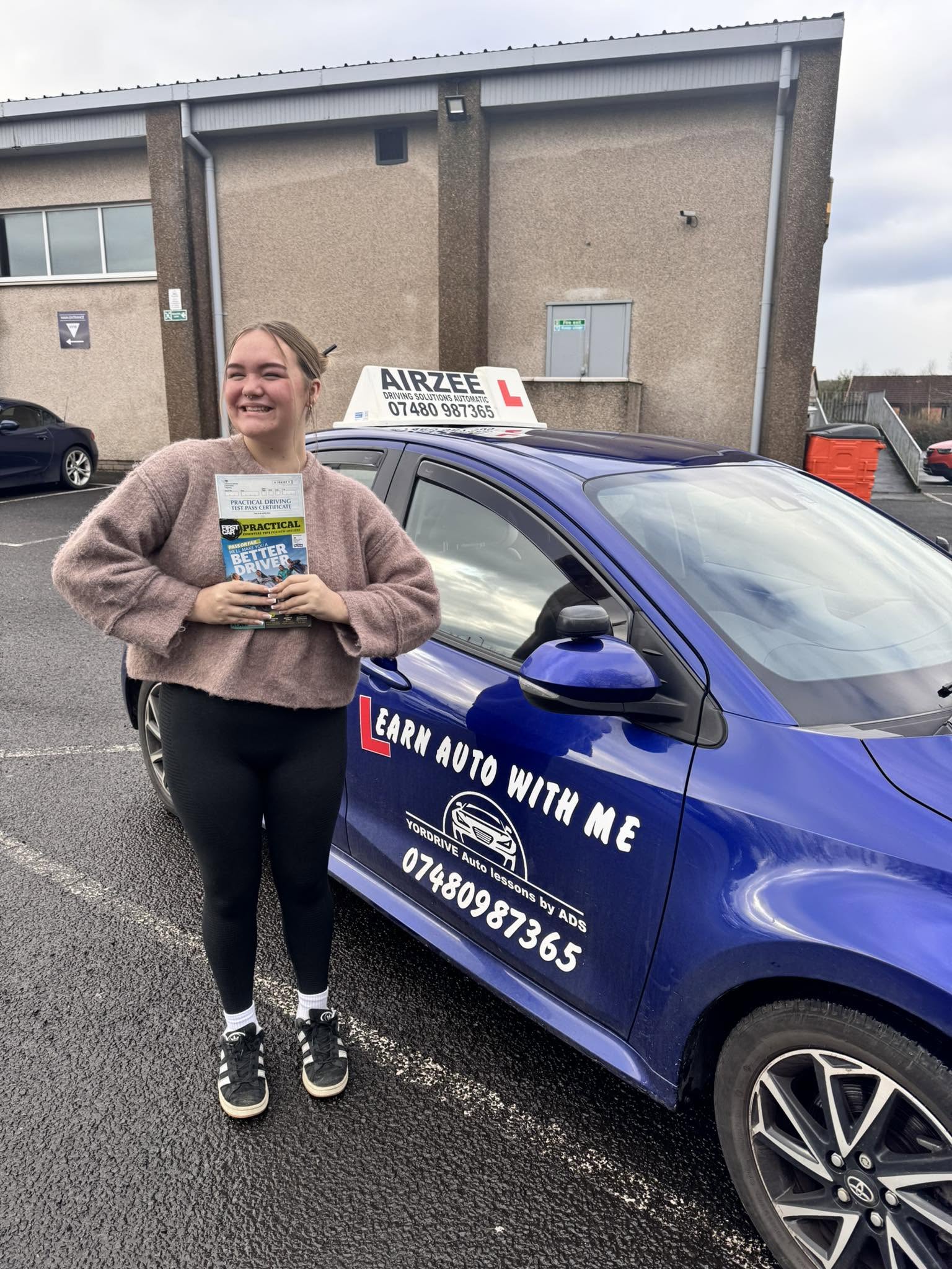 YorDrive learner celebrating with practical driving test pass certificate, blue training car