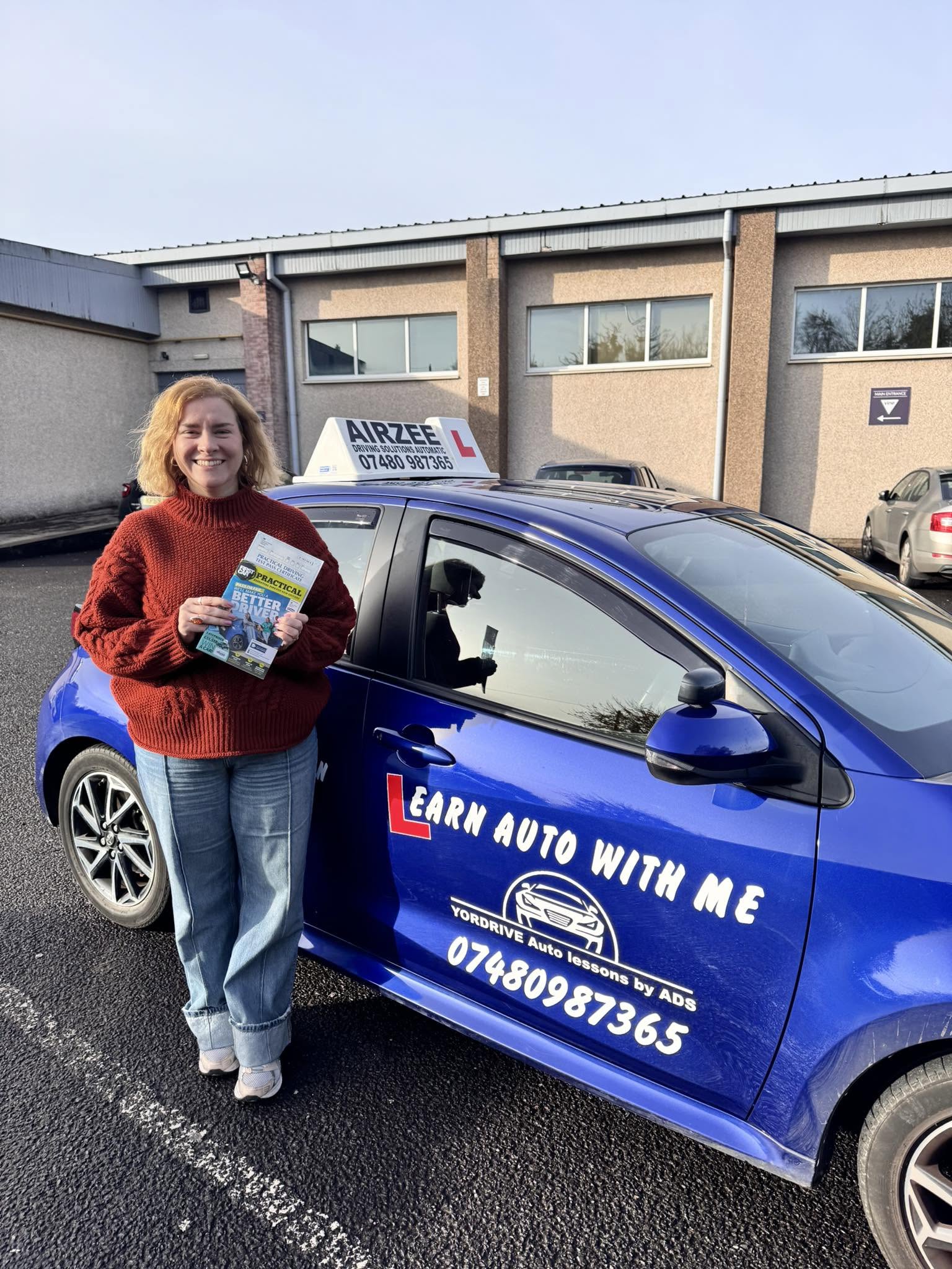 YorDrive learner celebrating with practical driving test pass certificate, blue training car