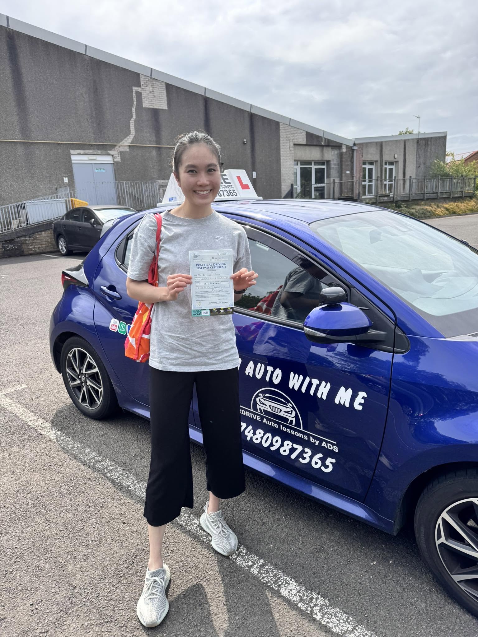 YorDrive learner celebrating with practical driving test pass certificate, blue training car