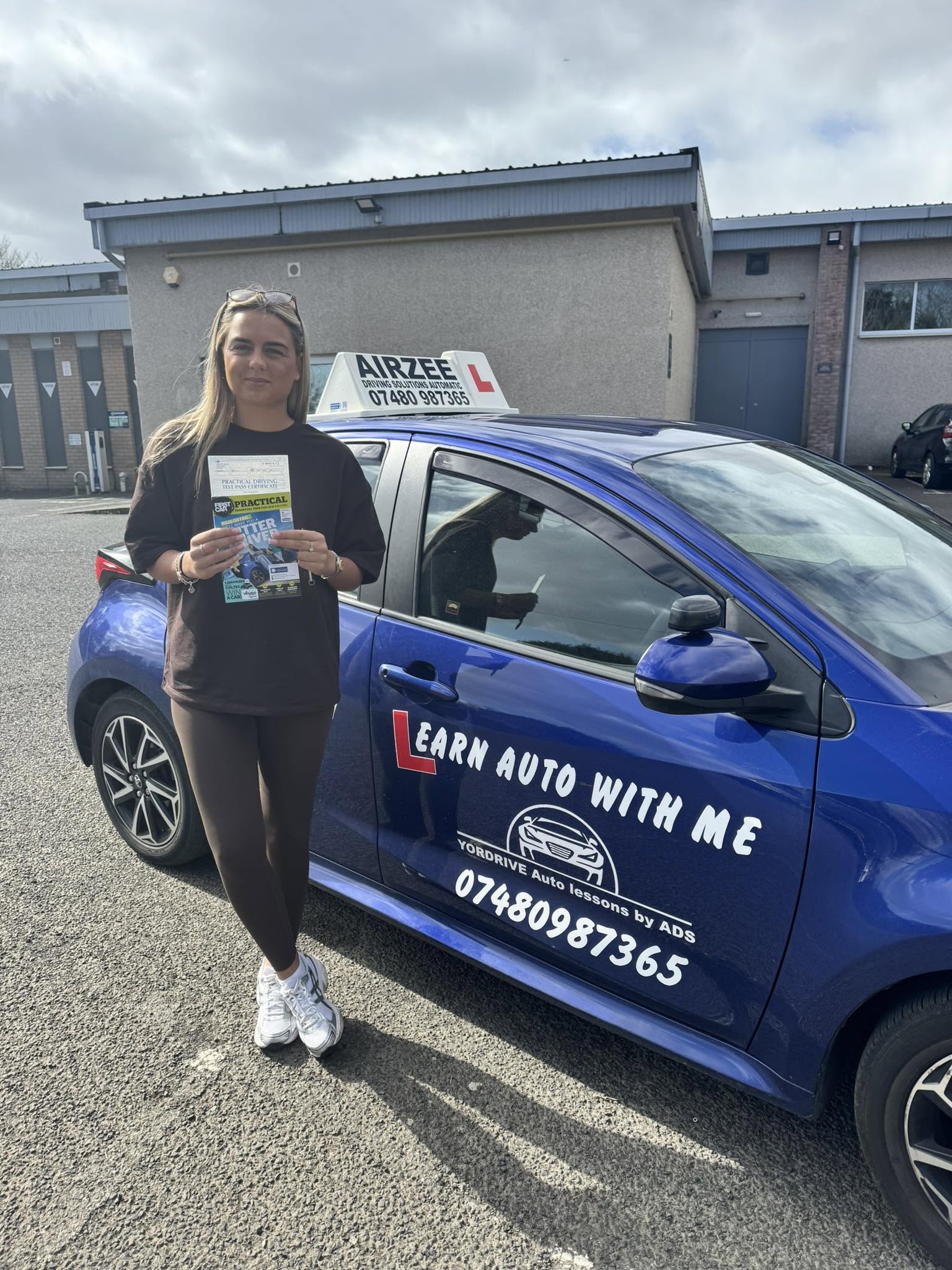 YorDrive learner celebrating with practical driving test pass certificate, blue training car