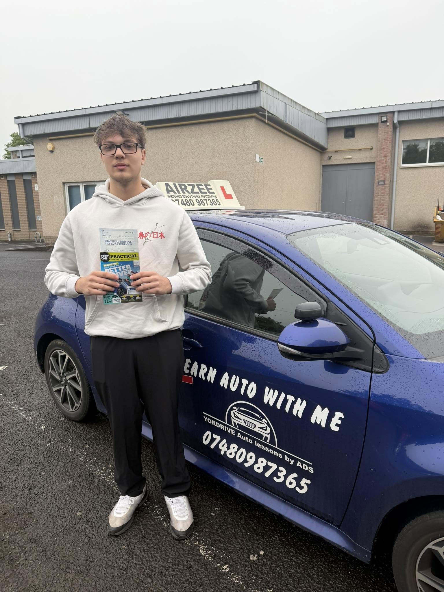 YorDrive learner celebrating with practical driving test pass certificate, blue training car