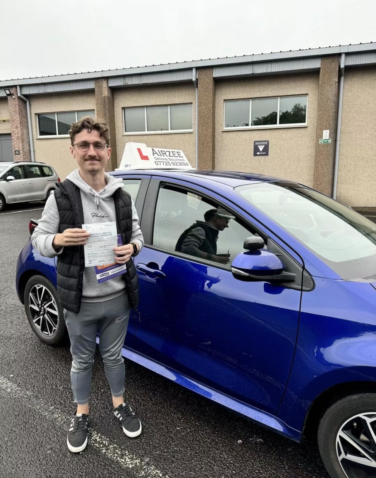 YorDrive learner celebrating with practical driving test pass certificate, blue Airzee training car